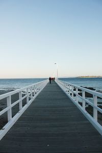 Man walking on pier over sea