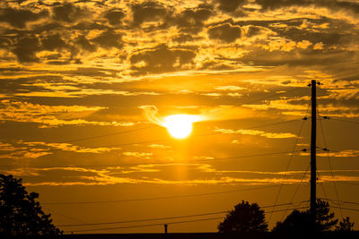 Low angle view of silhouette electricity pylon against sky during sunset