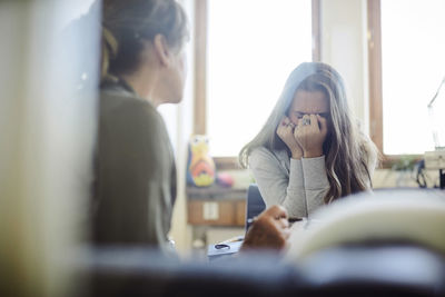 Displeased teenage girl talking to therapist at wellness center