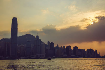 Scenic view of sea by buildings against sky during sunset