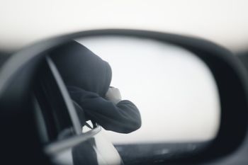 Reflection of man on side-view mirror