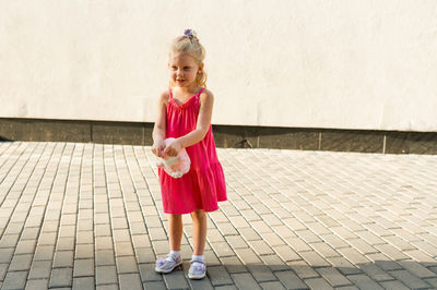 Portrait of young woman standing against wall