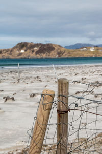 Wooden posts on beach against sky