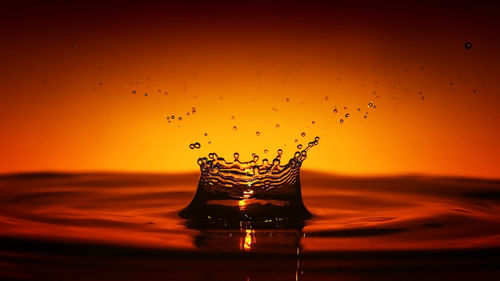 Close-up of water splashing in sea against sky during sunset