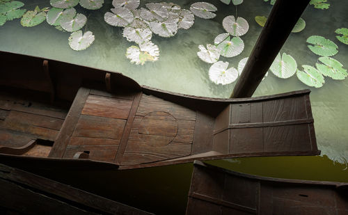 High angle view of traditional ferry moored by lilypads on canal