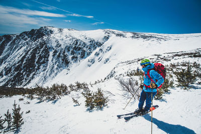 Person skiing on snowcapped mountain against sky