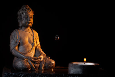 Close-up of buddha statue with illuminated candle