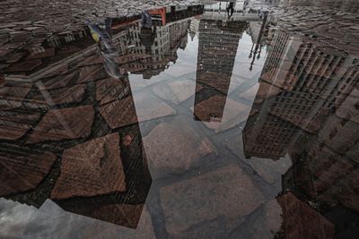 High angle view of buildings reflecting in puddle on footpath
