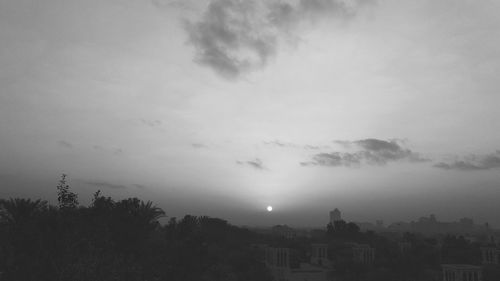 Silhouette trees and buildings against sky during sunset