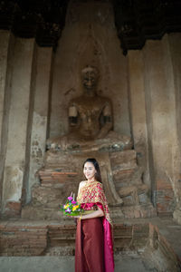 Woman standing against buddha statue at temple