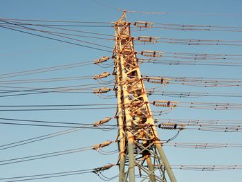 Low angle view of electricity pylon against clear sky