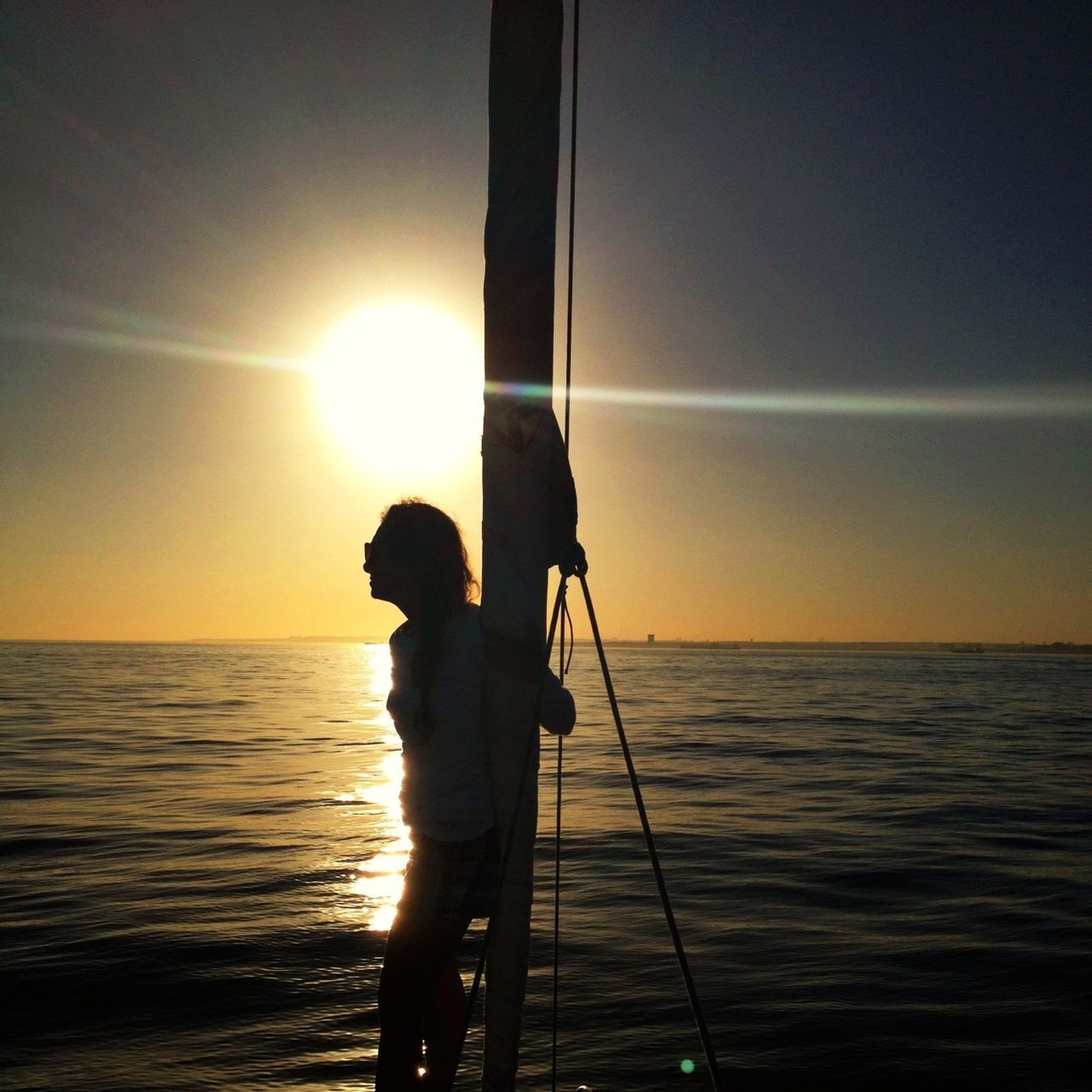 sea, water, horizon over water, sunset, leisure activity, lifestyles, silhouette, sun, standing, sky, rear view, scenics, men, reflection, three quarter length, beauty in nature, person, tranquility