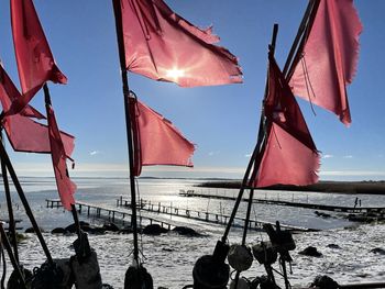 Low angle view of flags at beach against sky