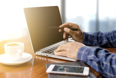 Midsection of man using laptop on table