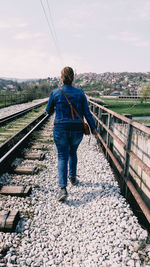 Rear view of woman walking by railroad track