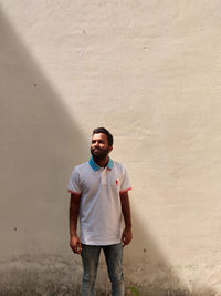 Portrait of young man standing against wall