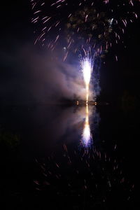 Firework display over lake against sky