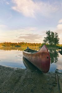 Boat moored on lake against sky during sunset