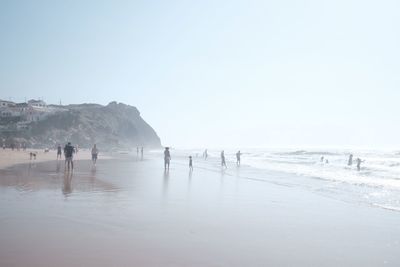 People on beach against clear sky