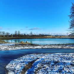 Scenic view of lake against clear blue sky