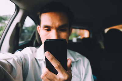 Close-up of man using mobile phone in car