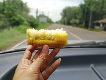 Cropped image of person holding ice cream in car