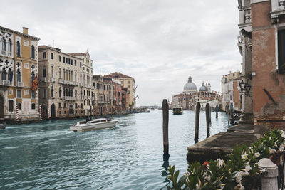 Canal amidst buildings in city against sky