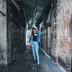 Full length portrait of woman standing against wall