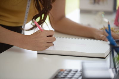 Midsection of woman reading book on table