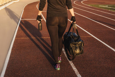 Low section of woman walking on running track