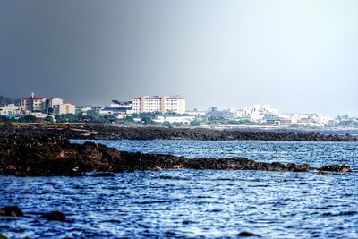 Sea and buildings against clear sky