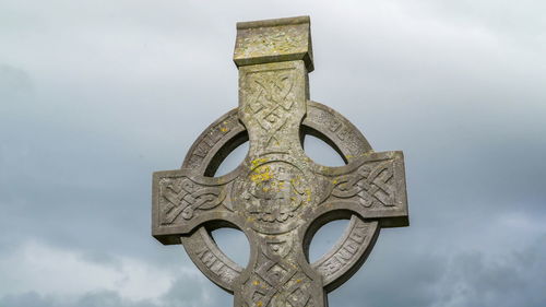 Low angle view of cross sculpture against sky