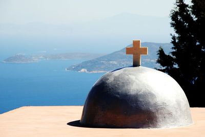 Close-up of cross on sea against sky