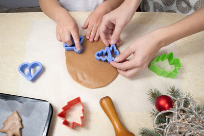 Mom and little daughter with cookie cutters make cookies from dough in the home kitchen. 