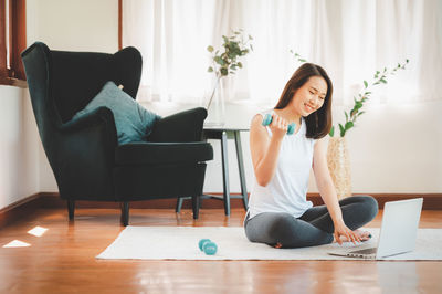 Woman using phone while sitting on chair at home