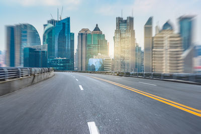 Road amidst buildings in city against sky