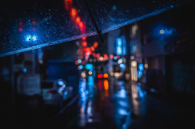 Illuminated city seen through wet glass window
