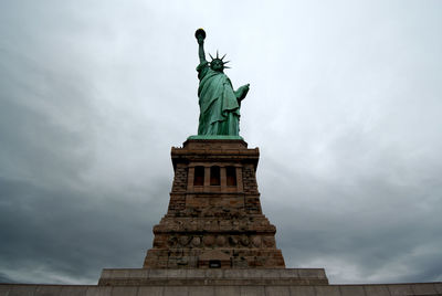 Low angle view of statue of liberty against cloudy sky