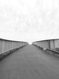 Empty road along bridge against sky