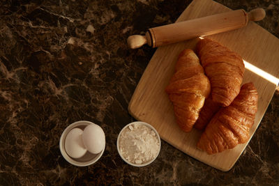 Croissants on a cutting board and some ingredients on a table. 