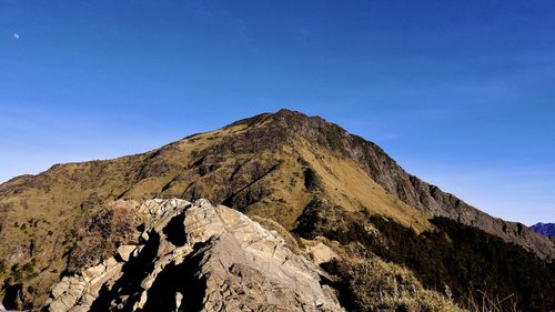 Low angle view of rocky mountain against blue sky