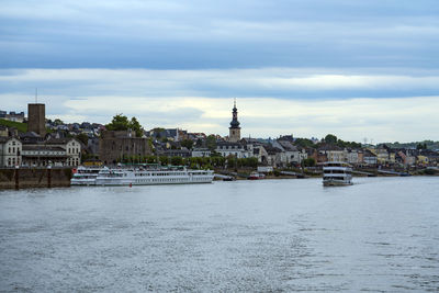 View of buildings by river against cloudy sky