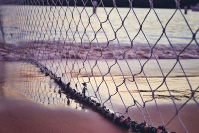 View of sea seen through chainlink fence