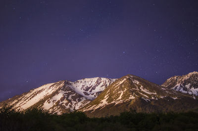 Scenic view of snowcapped mountains against sky at night
