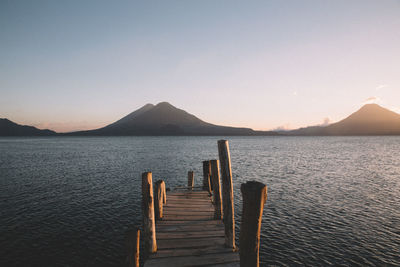 Wooden posts in sea against clear sky