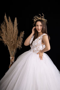Portrait of young woman against black background