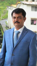 Portrait of businessman in blue suit standing against building