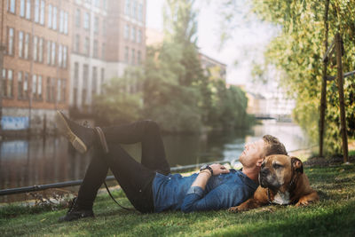 Young man lying down with his dog in park