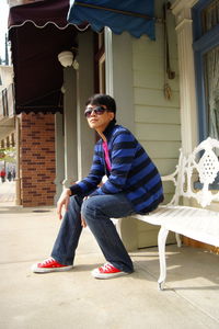 Young man wearing sunglasses while sitting on bench