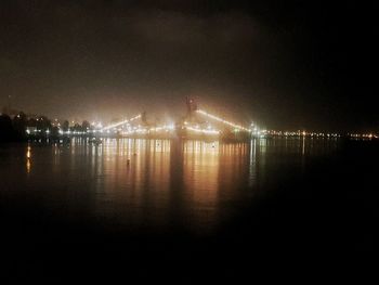 Illuminated suspension bridge over water at night